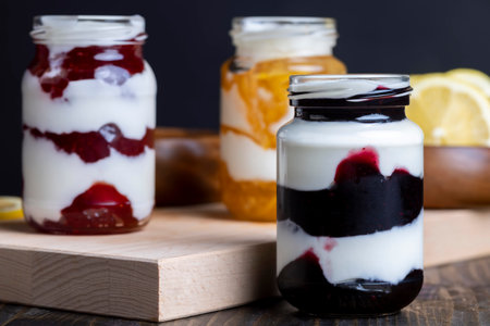 Yogurt made from fresh milk with the addition of sweet jam from lemon, strawberries and blueberries, packed in glass jars berry yogurtsの写真素材