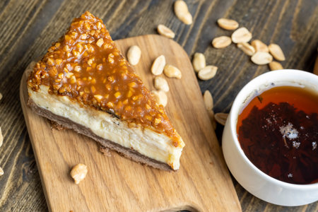 Cheesecake made of dairy products and peanuts in caramel, delicious dessert with peanuts cut into pieces for tea in a cafeの写真素材