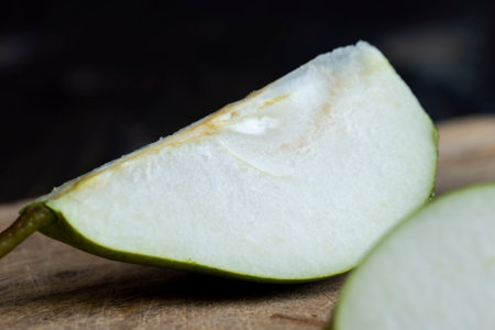Ripe green pear cut into pieces on the table, sliced into pieces green juicy but firm pearの写真素材