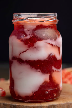 Fresh delicious milk yogurt with pomegranate flavor, yogurt with red sweet jam and red ripe pomegranate seedsの写真素材