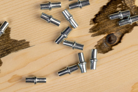 rivets for furniture are used to install shelves in cabinets, furniture metal fittings on a wooden board made of pine closeupの写真素材