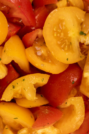 red and yellow tomatoes during salad preparation, preparation of salad from sliced tomatoes with spices and oilの写真素材