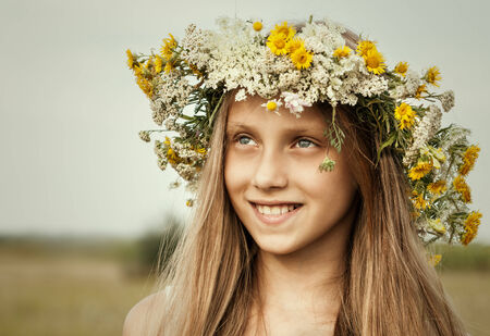 Portrait of young beautiful cute romantic happy ukrainian woman wearing a wreath of wild flowers in summer day, outdoors  Series of photos の写真素材