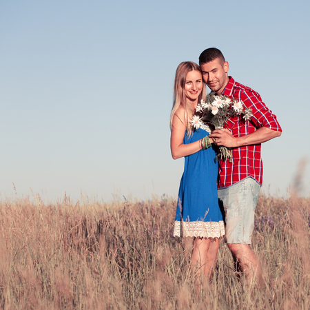 Love story. Beautiful young couple walking in meadow, outdoor. Portrait of stylish fashion man and woman posing in summer in field. Seriesの写真素材