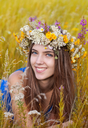 Portrait of young beautiful cute romantic  girl wearing a wreath of wild flowers in summer day, outdoors. Happy woman. Series of photosの写真素材