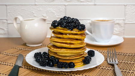 Pancakes. Sweet honey pouring over pancakes with berry fruit. Tasty breakfast food. Stack of american pancakes served with black currant and blackberry. Honey dripping down on dessert. Slow motionの写真素材