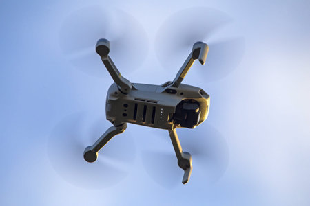 Drone flying in the blue sky. Radio-controlled quadcopter with a video camera for observing and...