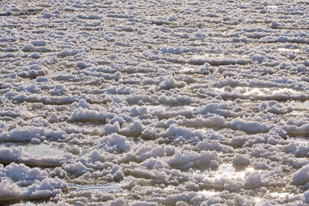 Ice floes float on a frozen river on a sunny winter day. Ice has formed on the Neris River in...