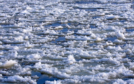 Ice floes float on a frozen river on a sunny winter day. Ice has formed on the Neris River in...