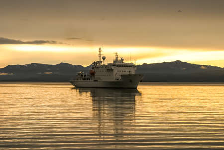 White ship at sunset and coast of Antarctica.の写真素材