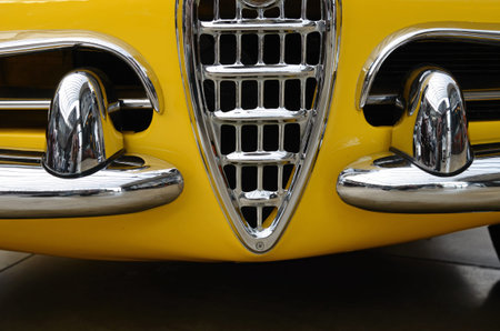 Interesting design of old yellow car with original grille and chrome bumper close up.