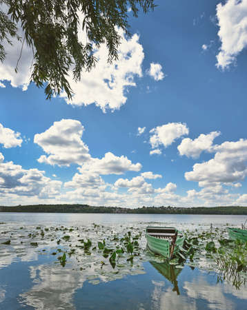 Mystical landscape with lonely boat on the pond on the background of clouds in pastel colors (meditation, idyll, journey - concept)の写真素材