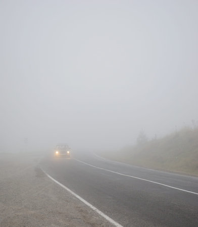 Landscape with a car on the road in the fog with headlights includedの写真素材