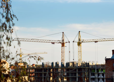 construction cranes and skeleton unfinished house against the sky