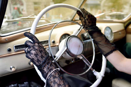 Women's hands in transparent gloves on the steering wheel of retro car. vintage styleの写真素材