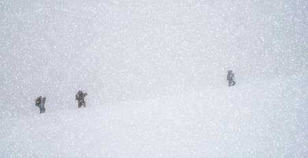 Group of travelers trekking in the mountains in the snow blizzard (International Day of Mountains, Tourism Day, try,  trial, test - concept)の写真素材
