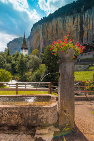 The picturesque landscape with flowers, a waterfall and canyon church in Lauterbrunnen in the Swiss Alps, Switzerland, Europeの写真素材