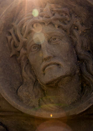 Face of Jesus Christ with a thorn crown on a grave at an old cemetery in sunlight.の写真素材