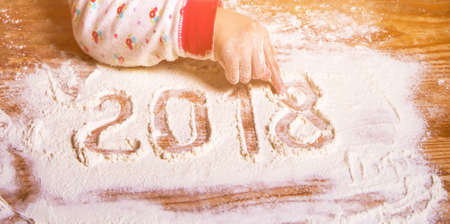 Inscription 2018 with a children's hand on a flour board (new year background, birth, childbirth, happiness - concept)の写真素材