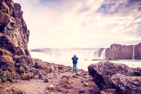 The photographer takes picturesque landscapes on one of the most spectacular waterfalls in Iceland Godafoss on the river Skjalfandafljot. Exotic countries. Amazing places.の写真素材