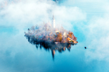 fabulous breathtaking landscape with a church on the island in the middle of the autumn forest in...
