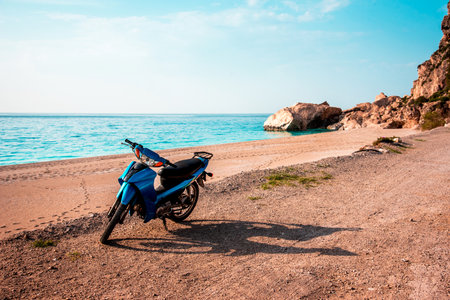 Summer landscape with a blue scooter by the sea on a background of rocks.の写真素材