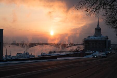 Frosty sunset over the municipal bridge in the city of Krasnoyarsk, Russia. The steam from the river and the building of river station on the street Dubensky.のeditorial素材