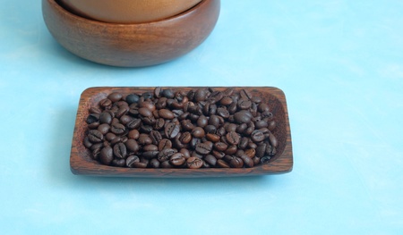 Roasted coffee beans in the wooden plate on a blue backgroundの写真素材