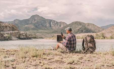 man with backpack using laptop outdoorsの写真素材