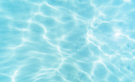 Blue water background with sun reflection in swimming pool. Summer background.