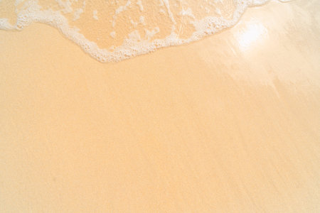 Soft wave of the sea on the sandy beach background. Top view.