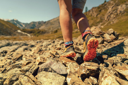 woman hiker legs walking on rocky trail in mountains, closeup
