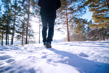 Man walking in winter forest. Close up of male legs on snow.の写真素材
