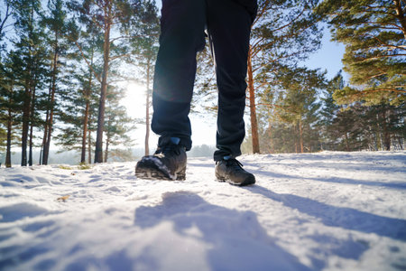 Close-up of the legs of a man walking in the winter forest