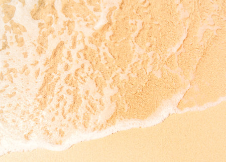 Soft wave of the sea on the sandy beach background. Top view.