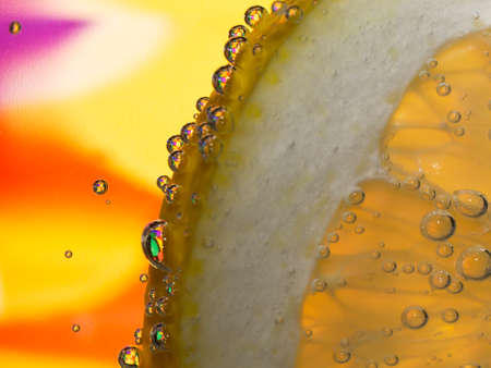 Macro photo of a lemon slice in bubbling water. Colorful background.の写真素材