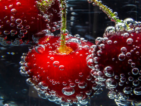 Macro photo of red cherries in bubbling water.の写真素材