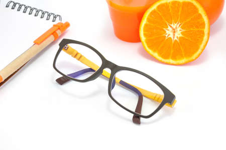 Modern Glasses and Notepad Nearing a group of Orange isloated on white backgroundの写真素材