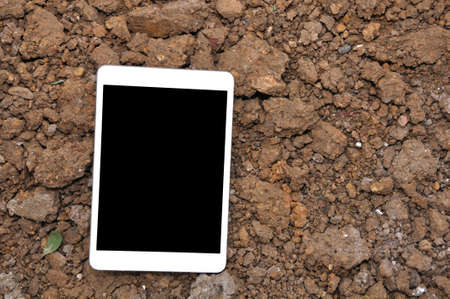 White Cell phone On Soil Surface.の写真素材