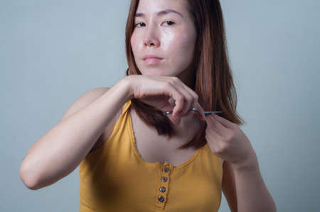 Portrait of Asian woman  in yellow shirts are cut her hair with scissors.の写真素材