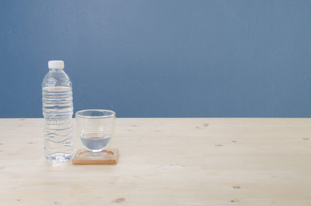 Wooden Table with drinking water in glass and blue cement background.