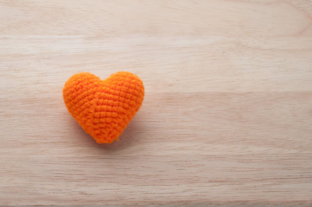 Knitted fabrics heart shape on wooden background, valentine day greeting card idea.