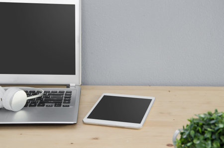 Office Desk with notebook, tablet and earphone. View from front with notepad space.の写真素材