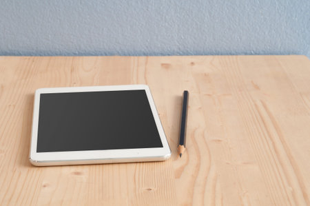 Office desk with Tablet and Pencil on wood floors and blue sky cement background, Business concept...