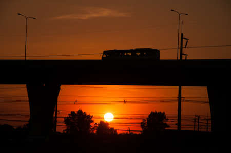 Image of Silhouette travel bus on highway and big sun set in the evening.の写真素材