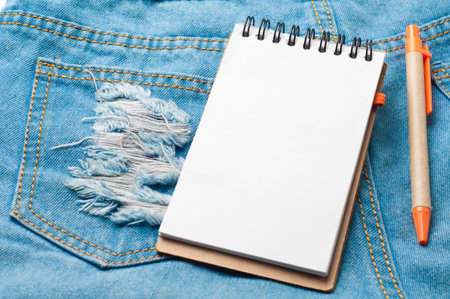 Notepad paper and pencil on blue jean texture.