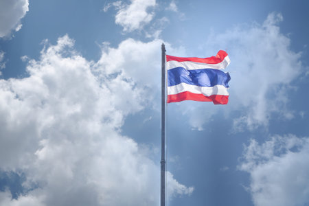 Thailand flag with flagstaff on cloudy sky background.