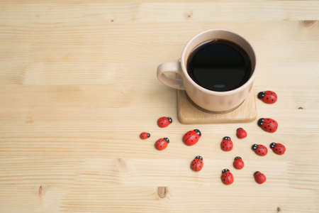 Wooden dining table with black coffee and red ladybug finding some sugar concept.の写真素材