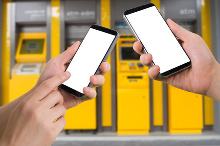 human hand hold and touch smartphone, tablet, cell phone with blank screen, virtual internet banking on blurry cash machines background, transfer money concept.の写真素材