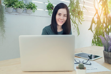 Office table with laptop and blank screen on laptop, Asian woman smile face. wood table with office...